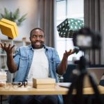 man recording video blog while unpacking presents