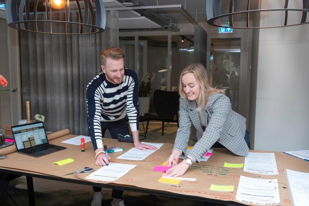 Collega's samenwerken aan tafel met notities en laptop.